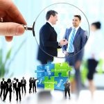 Magnifying glass on businessmen and puzzle pieces