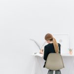 Woman writing at minimalist white desk
