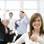 Smiling woman giving thumbs up, celebrating colleagues