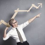 Businessman celebrating growth with upward arrow graph